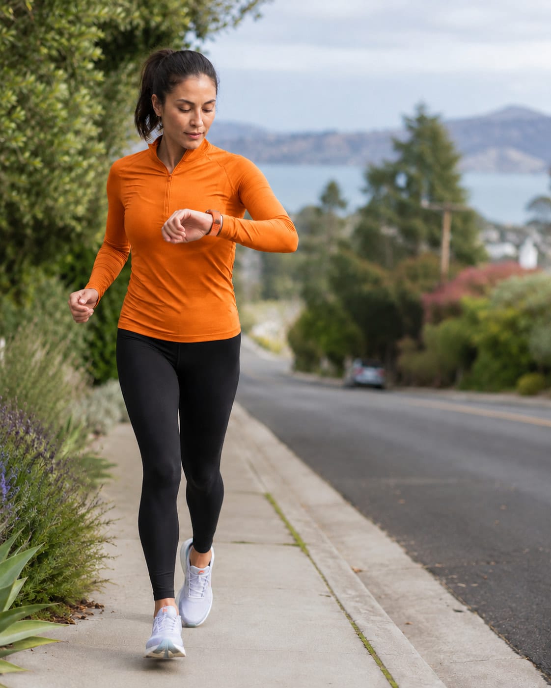 Woman in running clothes checking her sports watch while training on a road